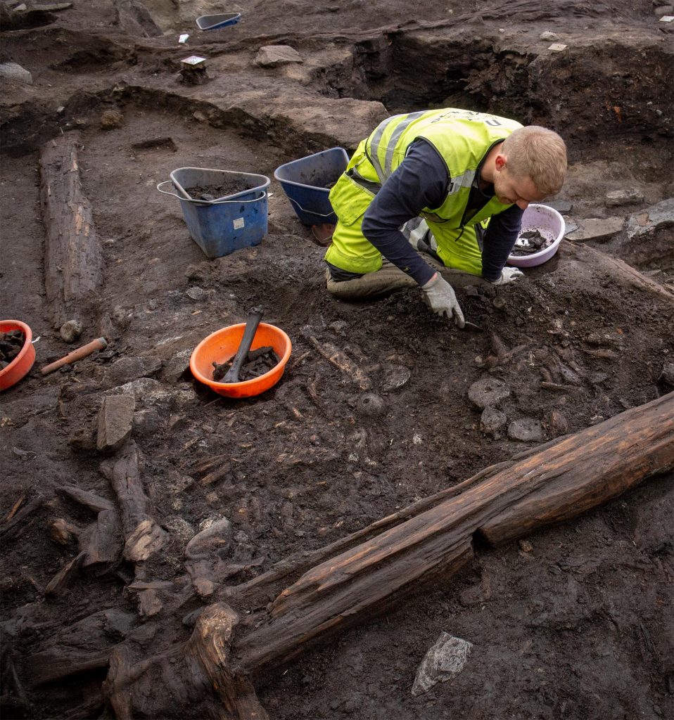 Fig. 8: Archaeologist Kristoffer Grini excavating the area between Buildings 4 and 5. Situated directly outside the gable wall of Building 4 were several net-sinkers, possibly from a fishing-net hung here and collapsed in-situ. Photo: NIKU